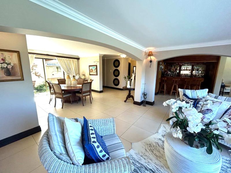 Spacious open-plan living area featuring tiled floors, an arched transition to a built-in bar, and sliding glass doors leading to the outdoor space.