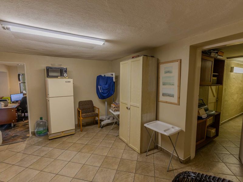 A functional utility space featuring tiled flooring and overhead fluorescent lighting, providing access to adjacent rooms.