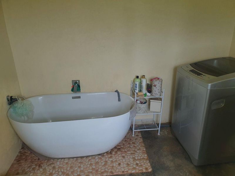 A bathroom featuring a modern freestanding bathtub with wall-mounted fixtures, set against a plain wall with a pebble tile floor inlay.