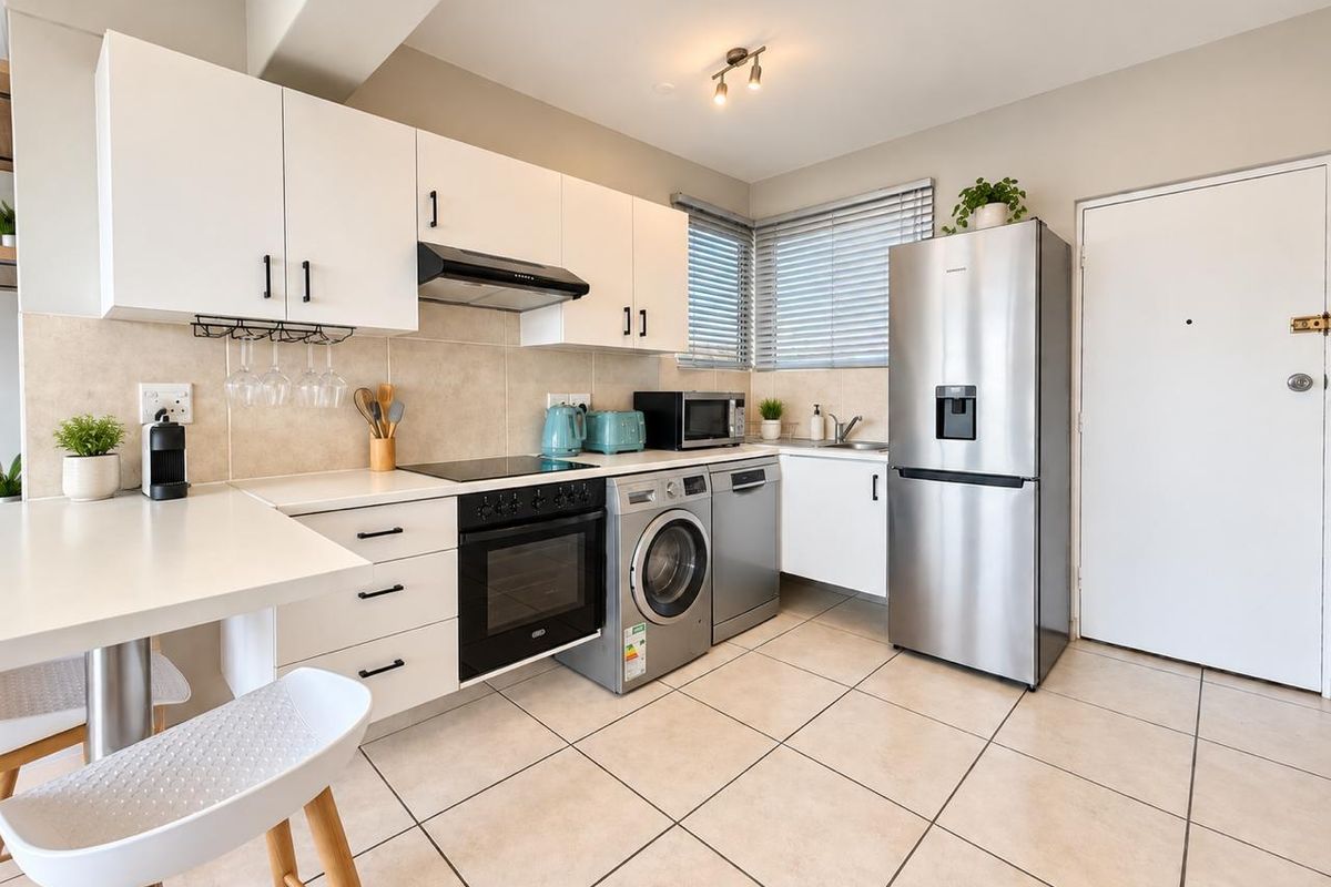Modern kitchen featuring white cabinetry, tiled flooring, integrated oven and hob, and a stainless steel sink with convenient under-counter appliance space.