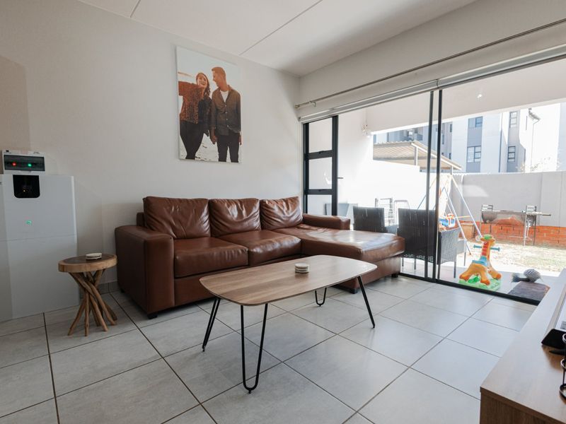 A bright living room featuring large sliding glass doors that provide direct access to an outdoor patio area and tiled flooring throughout.