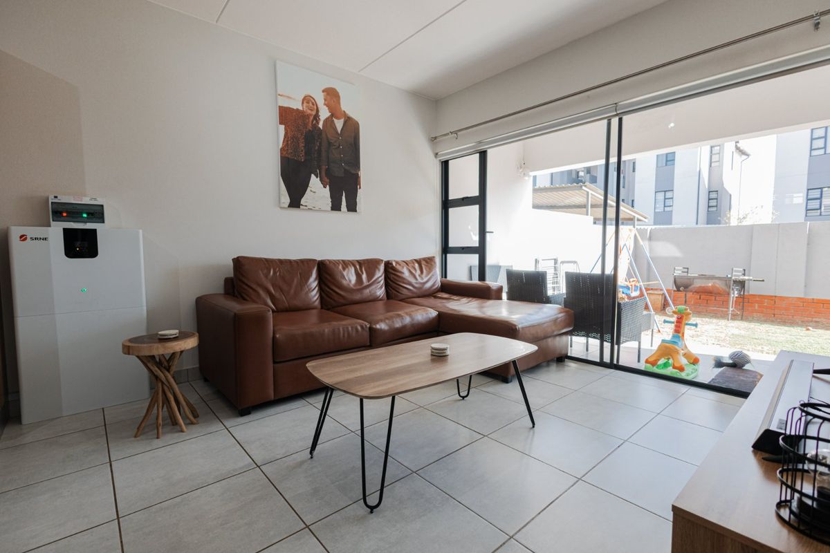 A bright living room featuring large sliding glass doors that provide direct access to an outdoor patio area and tiled flooring throughout.