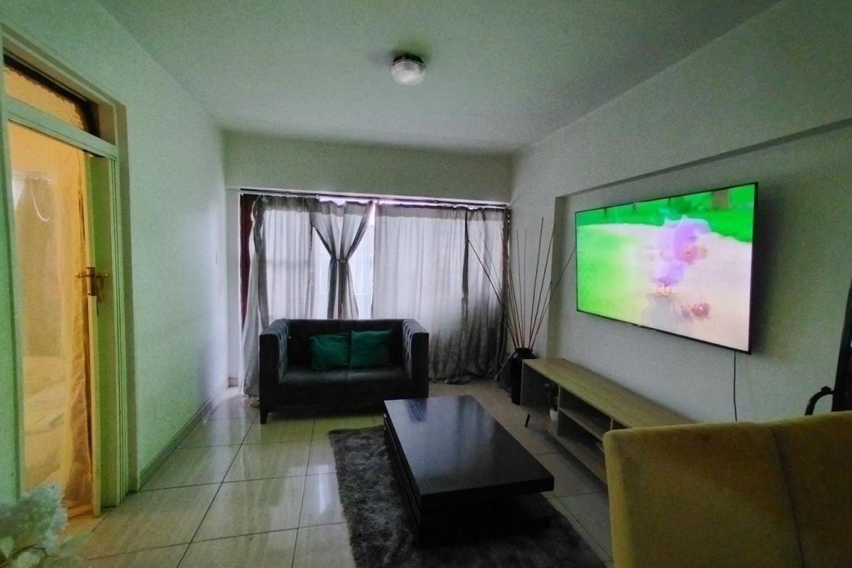 A living room featuring tiled flooring and a ceiling light fixture, providing a functional space for relaxation.