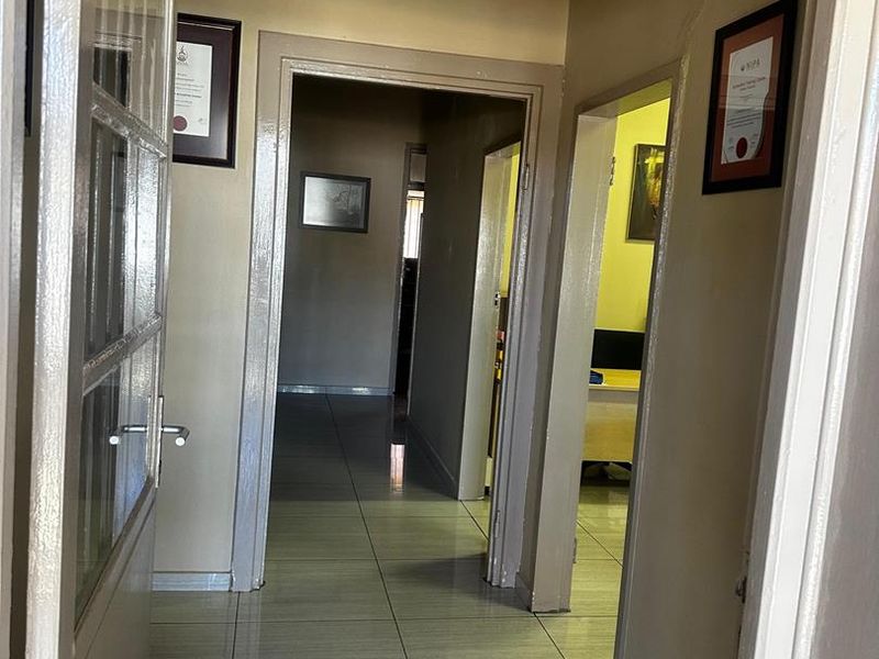 A functional hallway with tiled flooring connecting multiple rooms, featuring neutral wall tones and standard door frames.