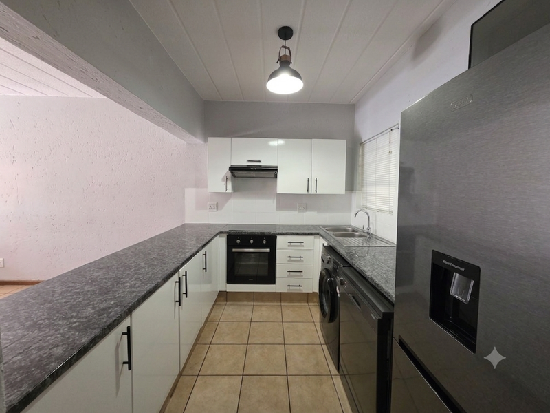 A modern, well-maintained kitchen featuring white cabinetry, granite countertops, integrated appliances, and tiled flooring, offering a clean and functional workspace.