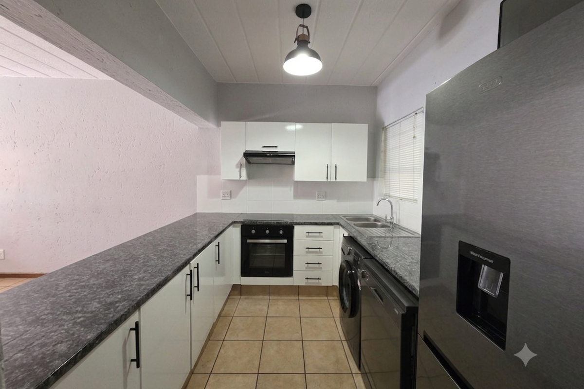 A modern, well-maintained kitchen featuring white cabinetry, granite countertops, integrated appliances, and tiled flooring, offering a clean and functional workspace.