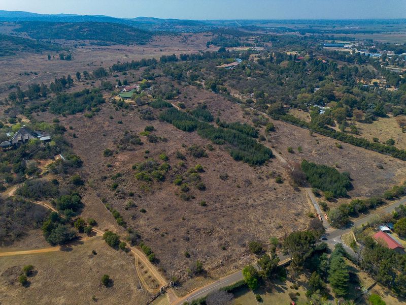 An aerial view of a large, undeveloped residential land parcel featuring natural vegetation and surrounding rural landscape.