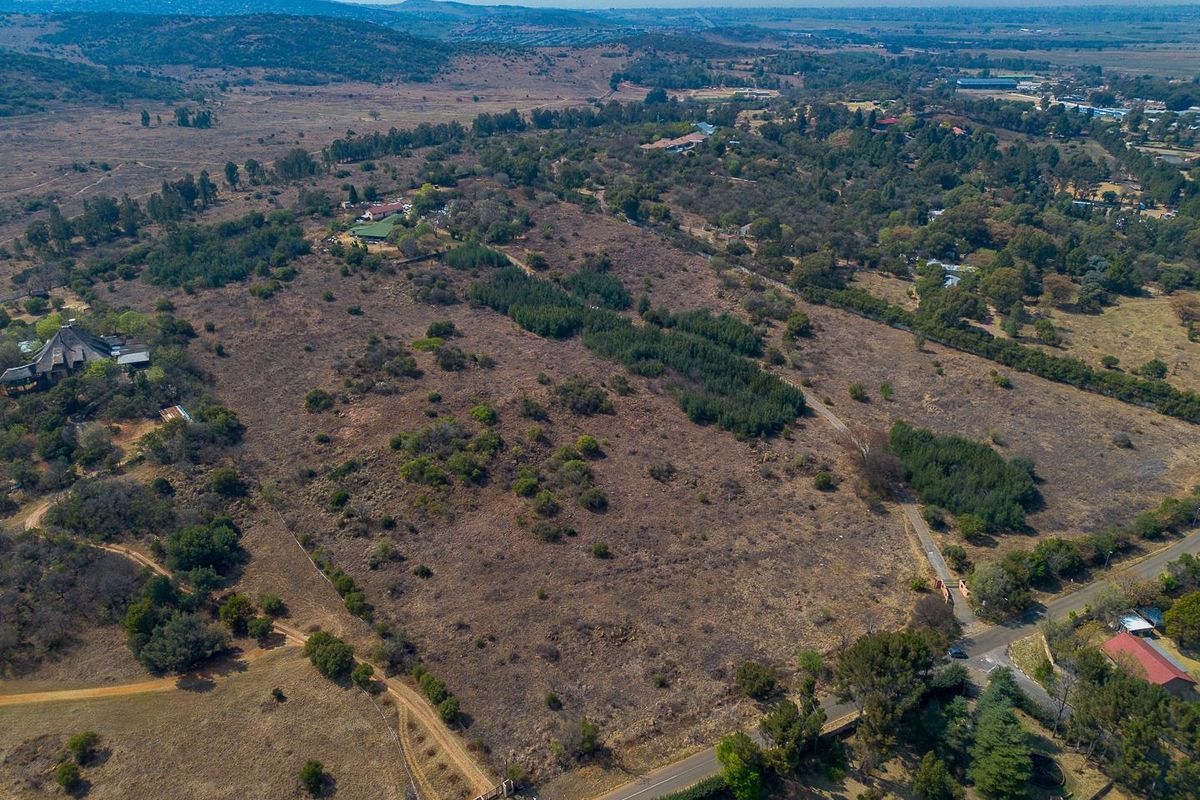 An aerial view of a large, undeveloped residential land parcel featuring natural vegetation and surrounding rural landscape.