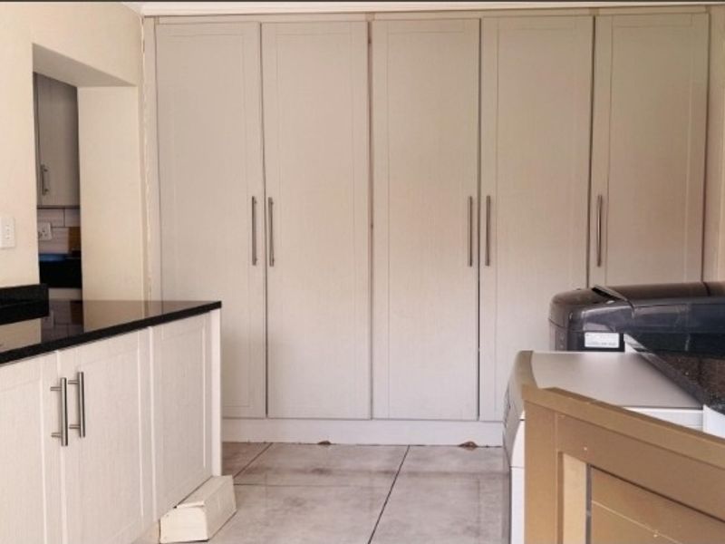 A functional laundry area featuring extensive built-in cabinetry, granite countertops, and tiled flooring, providing ample storage and workspace.