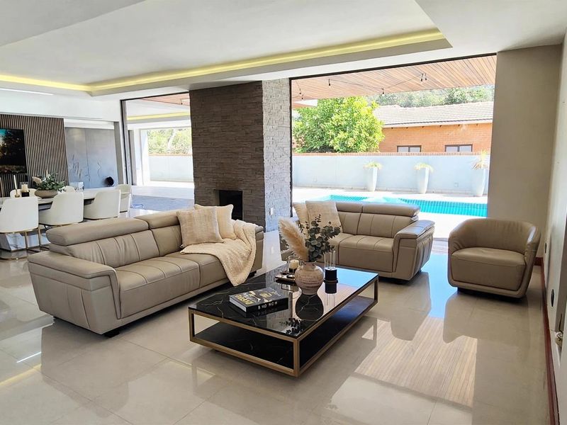 Spacious open-plan living and dining area featuring modern stone fireplace, recessed lighting, and seamless flow to the outdoor pool patio through large sliding doors.