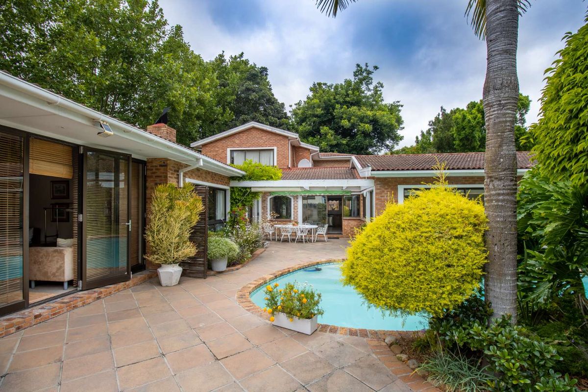 A spacious rear courtyard featuring a swimming pool, tiled patio area, and direct access to the home through large sliding glass doors.