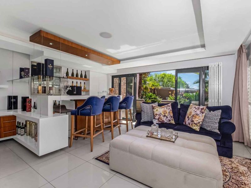 A modern, well-appointed home bar area featuring a built-in counter, recessed lighting, and seamless access to the outdoor patio through bi-fold glass doors.