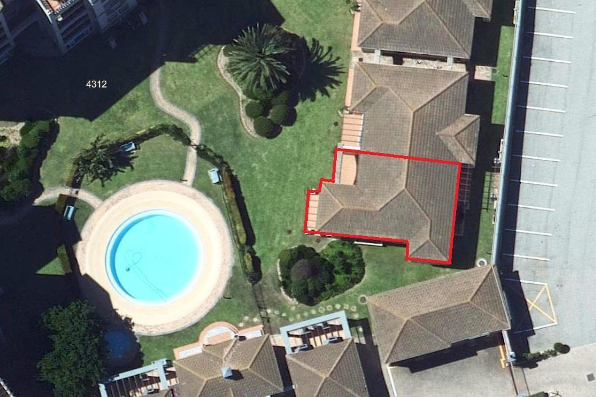 Aerial view of the townhouse complex showing the property layout, tiled roof structure, surrounding landscaped gardens, and communal swimming pool area.