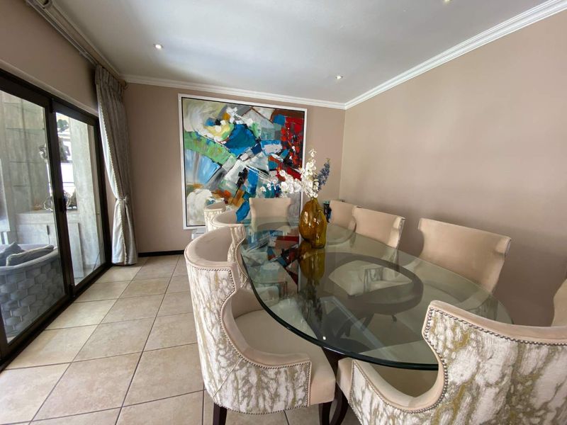 A well-maintained dining room featuring tiled flooring, crown molding, recessed lighting, and large sliding glass doors providing access to the outdoor area.