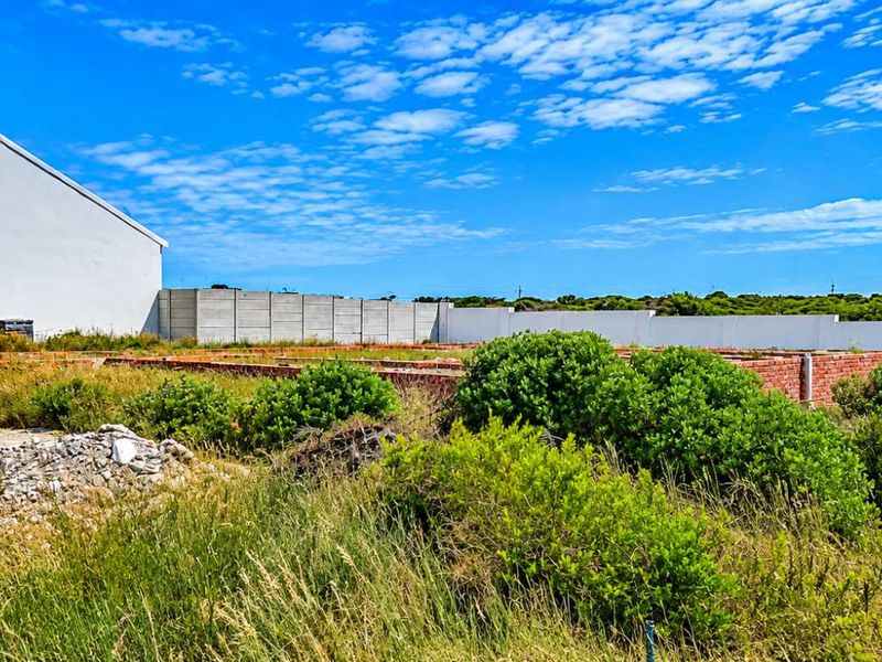 A vacant residential plot featuring an unfinished brick foundation, precast boundary walls, and overgrown vegetation, offering potential for future development.