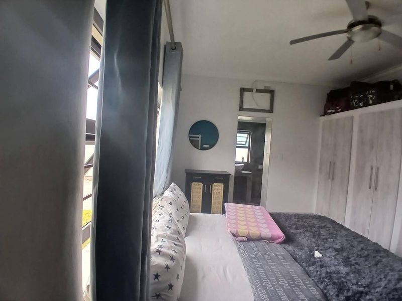 A bedroom featuring built-in cupboards and a ceiling fan, with an adjoining en-suite bathroom visible through the doorway.