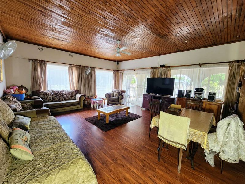 Spacious living area featuring warm timber ceilings, laminate flooring, and large sliding glass doors that provide ample natural light.