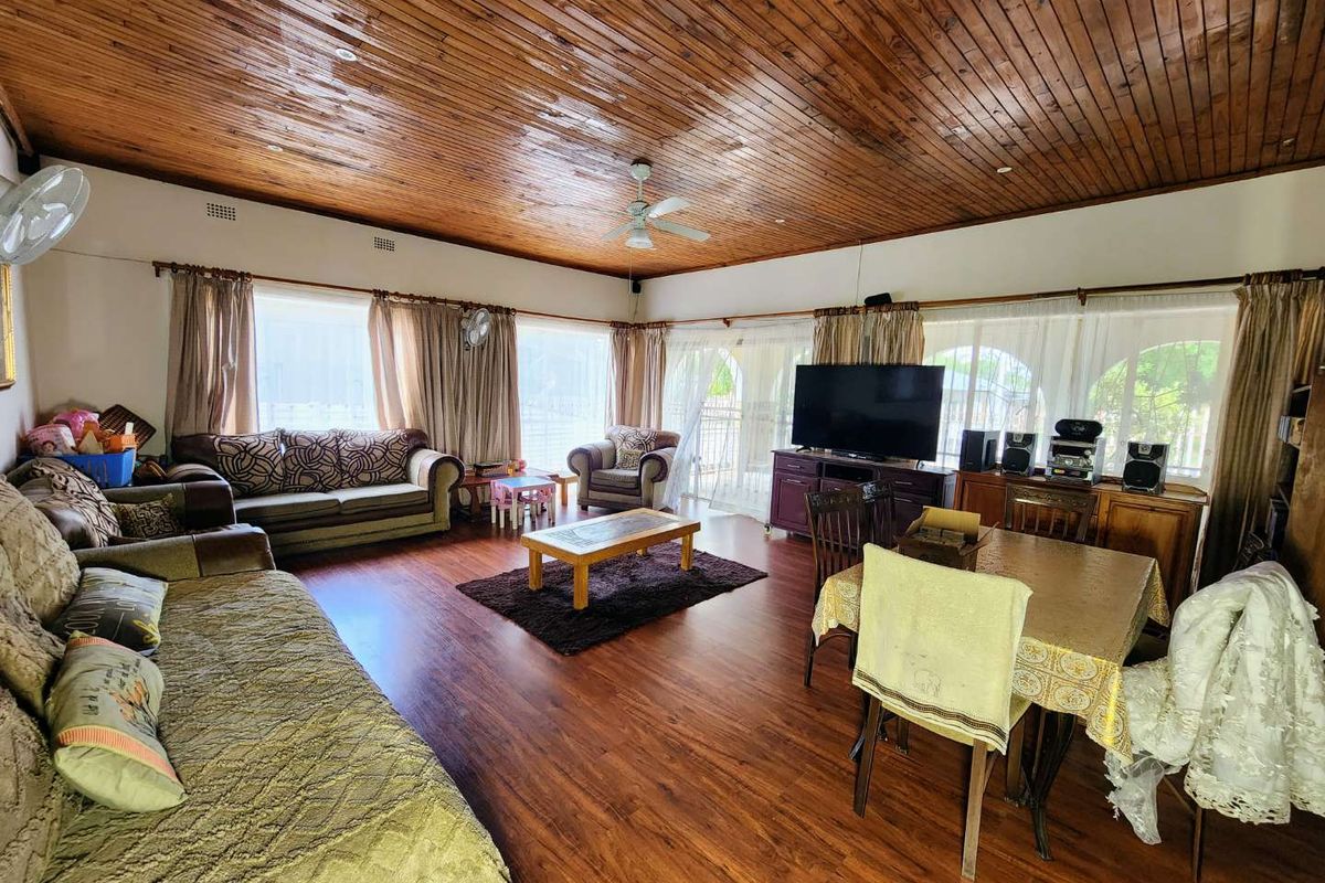 Spacious living area featuring warm timber ceilings, laminate flooring, and large sliding glass doors that provide ample natural light.