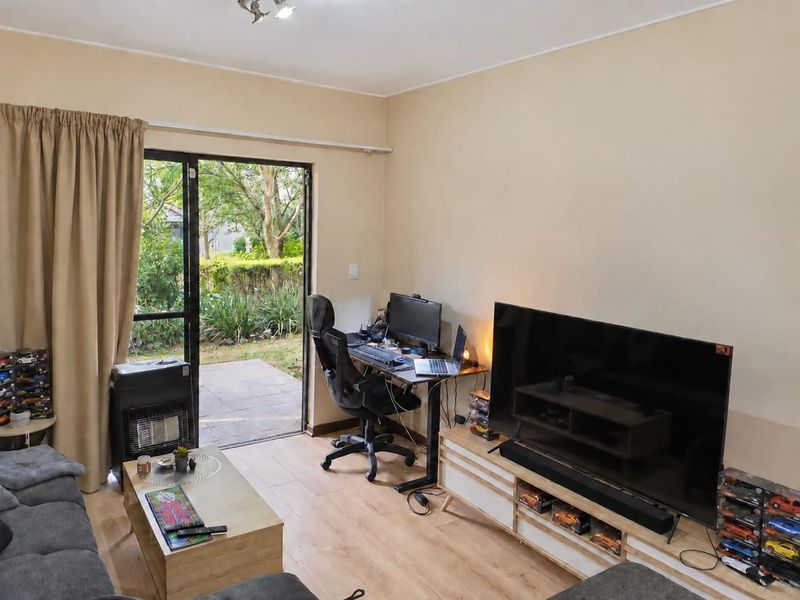 A living room featuring laminate flooring and a sliding glass door providing direct access to the garden area.
