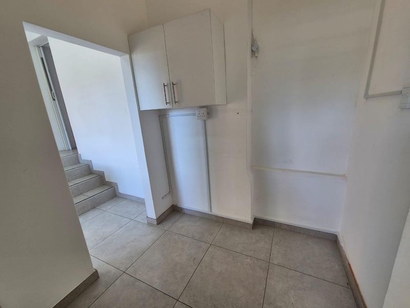 A functional laundry or utility area featuring tiled flooring and wall-mounted cabinetry, providing a practical space for laundry appliances and storage.