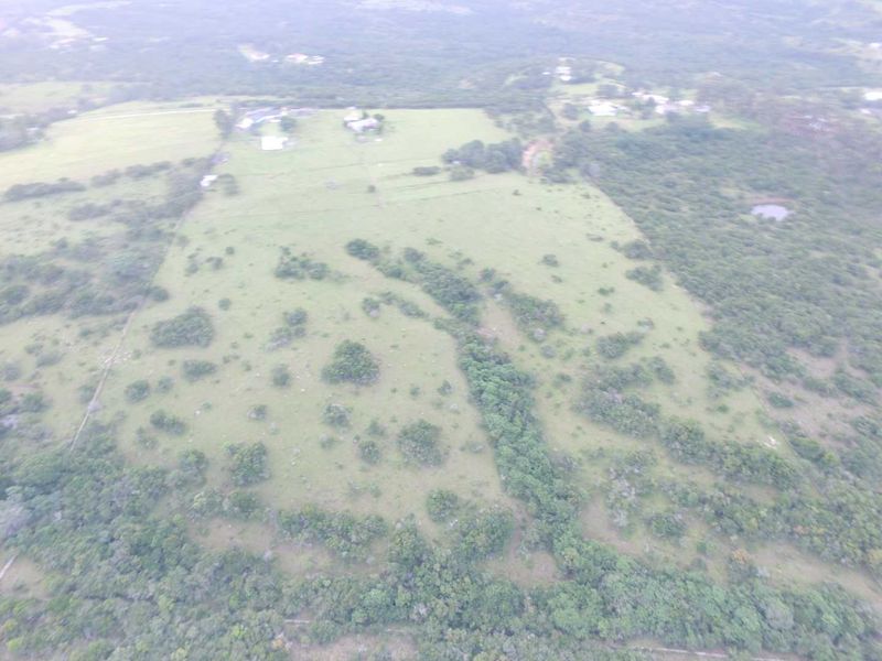 An aerial view of the expansive farm property, showcasing the open pasture land, natural vegetation, and surrounding rural landscape.