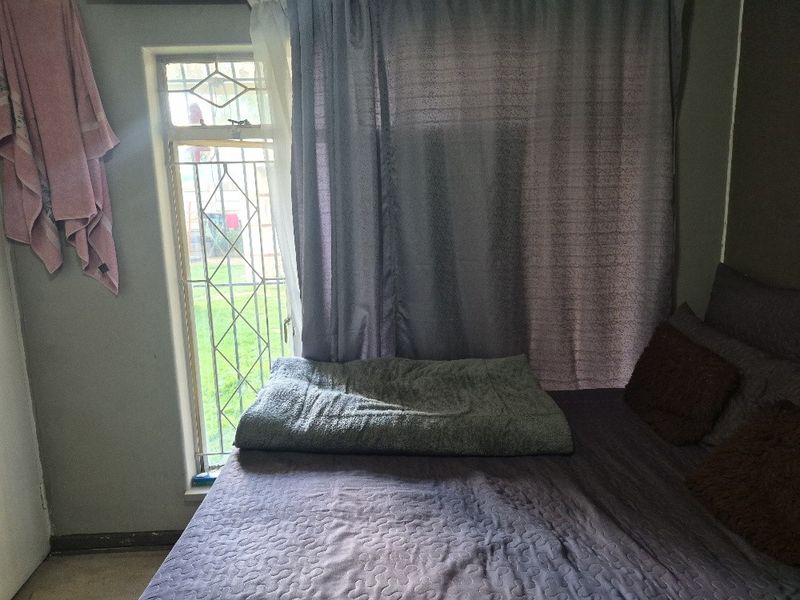 A bedroom featuring a window with a security gate and neutral wall finishes.