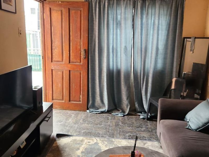 A living room featuring tiled flooring, decorative ceiling cornices, and a timber door leading to an exterior space.