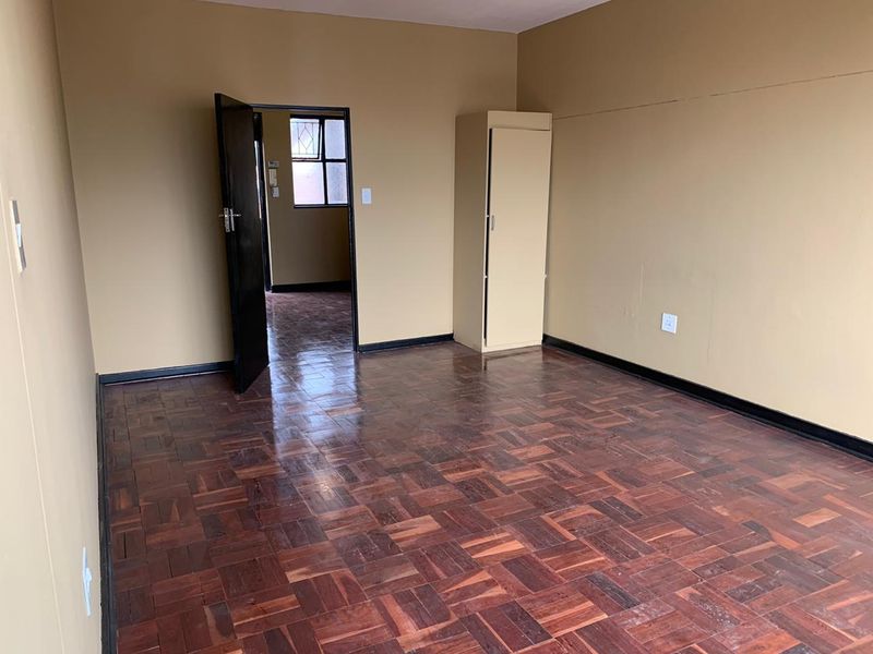 An empty bedroom featuring traditional parquet flooring and a built-in cupboard, offering a blank canvas for potential interior updates.