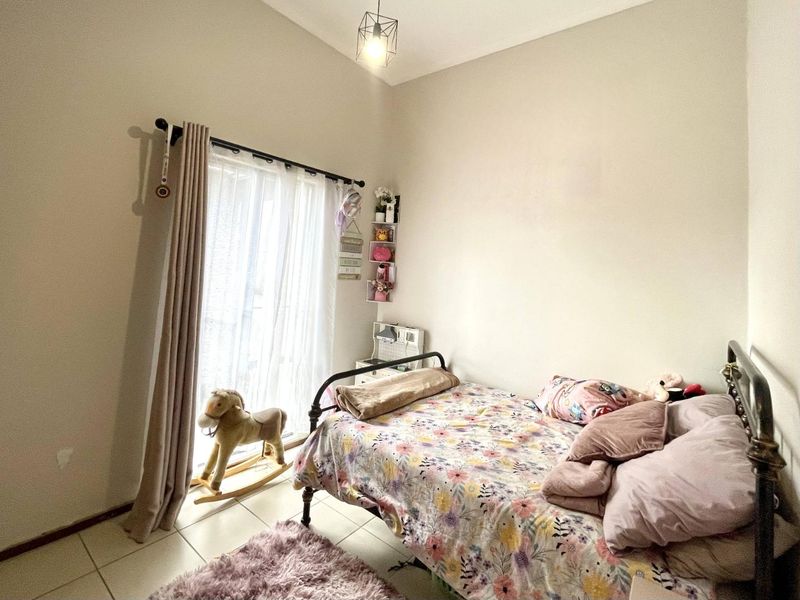 A bedroom featuring tiled flooring and a sliding glass door providing natural light, finished with a simple pendant light fixture.