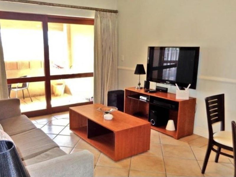 A living room featuring tiled flooring and a large sliding glass door providing access to an outdoor patio area.
