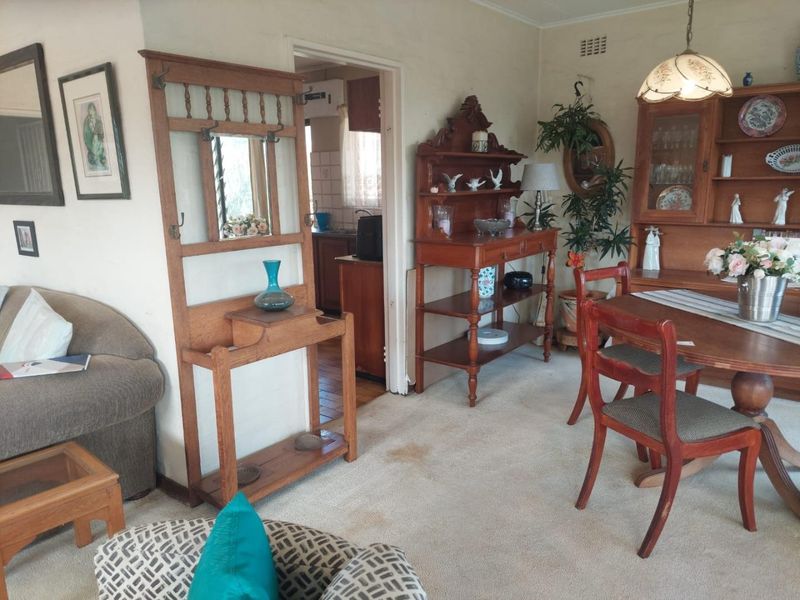 A living and dining area featuring carpeted flooring and a view into the adjacent kitchen space.