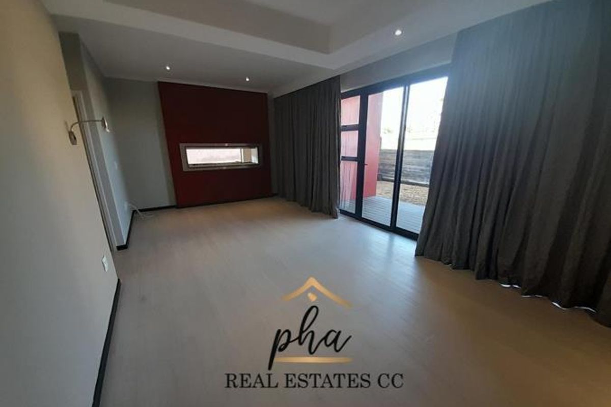 Spacious living room featuring a built-in fireplace, recessed ceiling lighting, and large sliding glass doors providing access to the outdoor area.