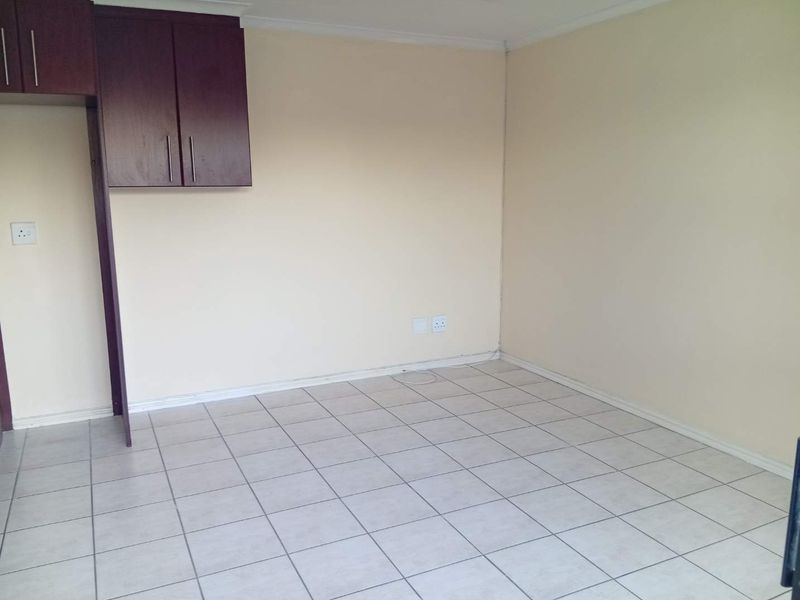 An empty kitchen area featuring tiled flooring and dark wood-finish built-in cabinetry, providing a blank canvas for customization.