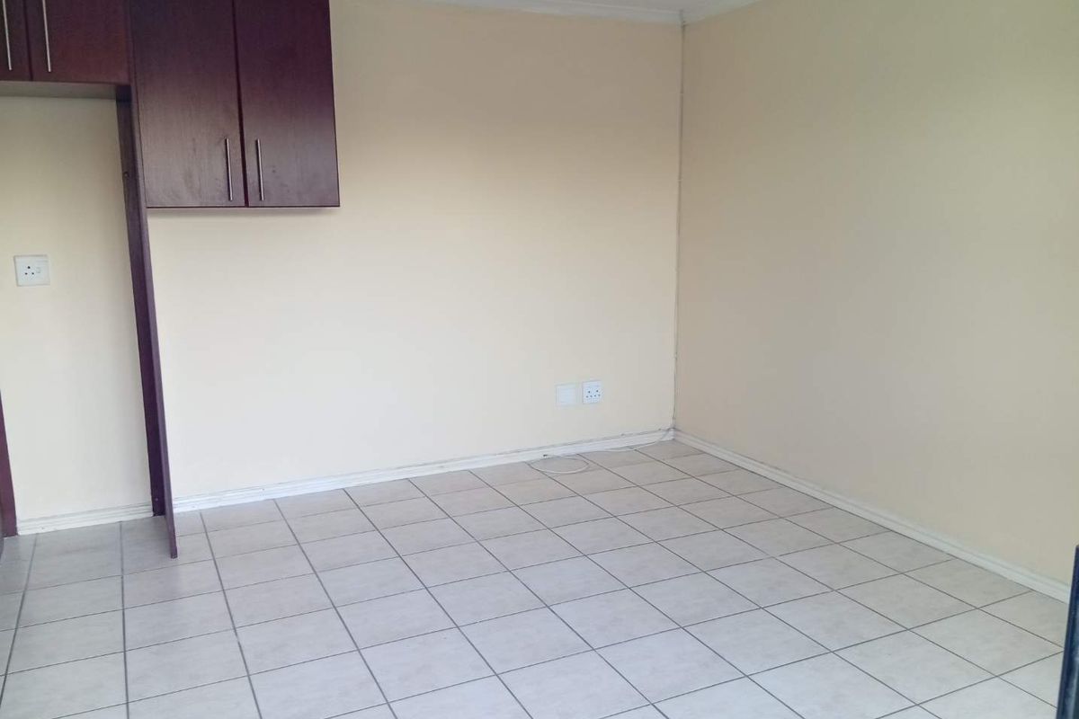 An empty kitchen area featuring tiled flooring and dark wood-finish built-in cabinetry, providing a blank canvas for customization.