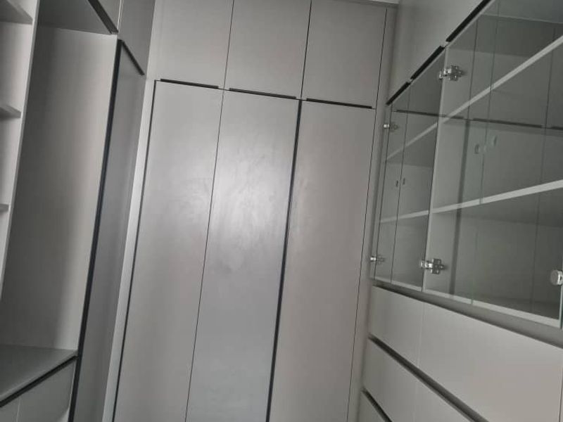 A modern walk-in closet or dressing area featuring extensive built-in cabinetry, glass-fronted storage, and sleek tiled flooring.