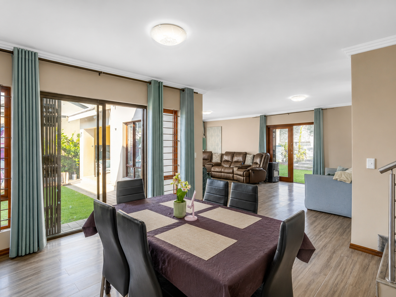 Spacious open-plan living and dining area featuring laminate flooring, large sliding glass doors leading to the garden, and a modern staircase.