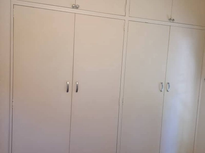 A bedroom featuring floor-to-ceiling built-in cupboards with white cabinetry and modern hardware.