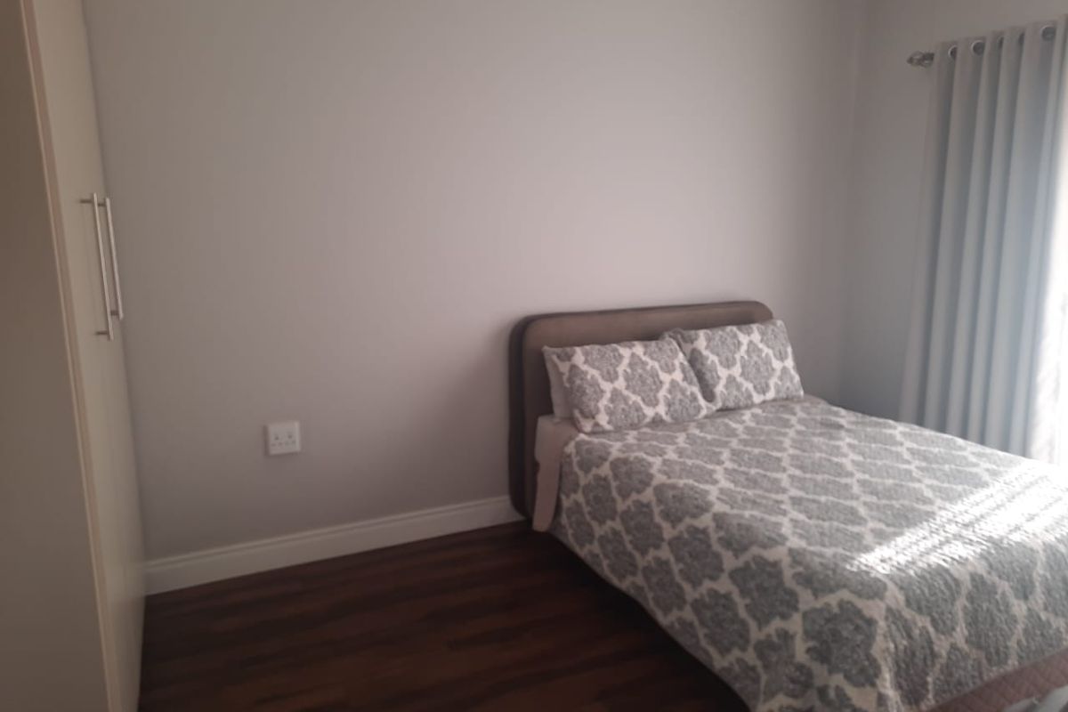 A well-maintained bedroom featuring laminate flooring, neutral wall tones, and a built-in wardrobe.
