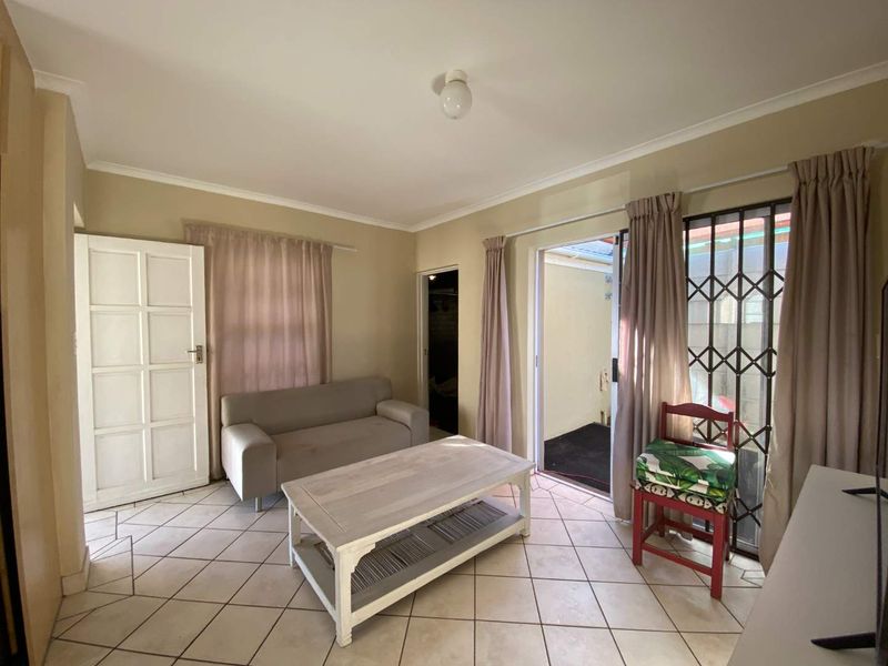 A living room featuring tiled flooring, a sliding door with a security gate, and direct access to an outdoor area.