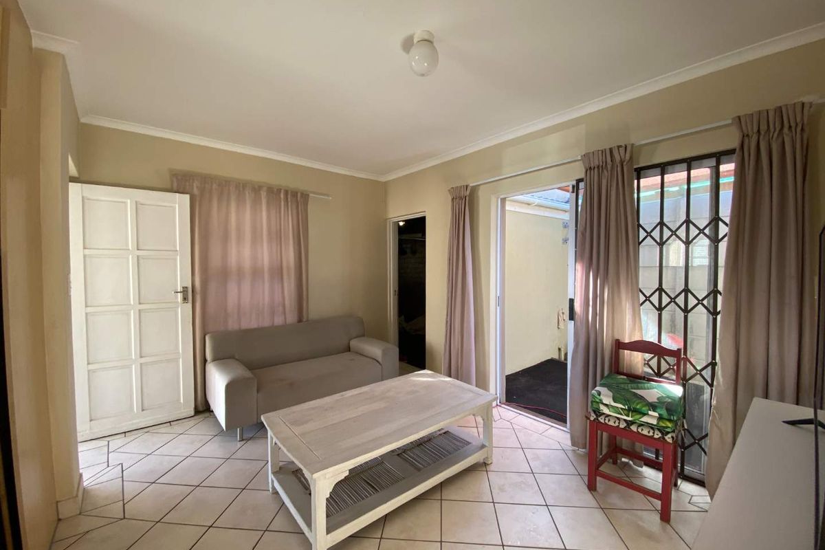A living room featuring tiled flooring, a sliding door with a security gate, and direct access to an outdoor area.