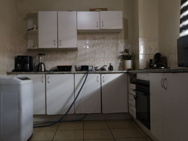 A functional kitchen featuring white built-in cabinetry, a tiled backsplash, and a built-in oven, offering a practical layout with potential for cosmetic updates.