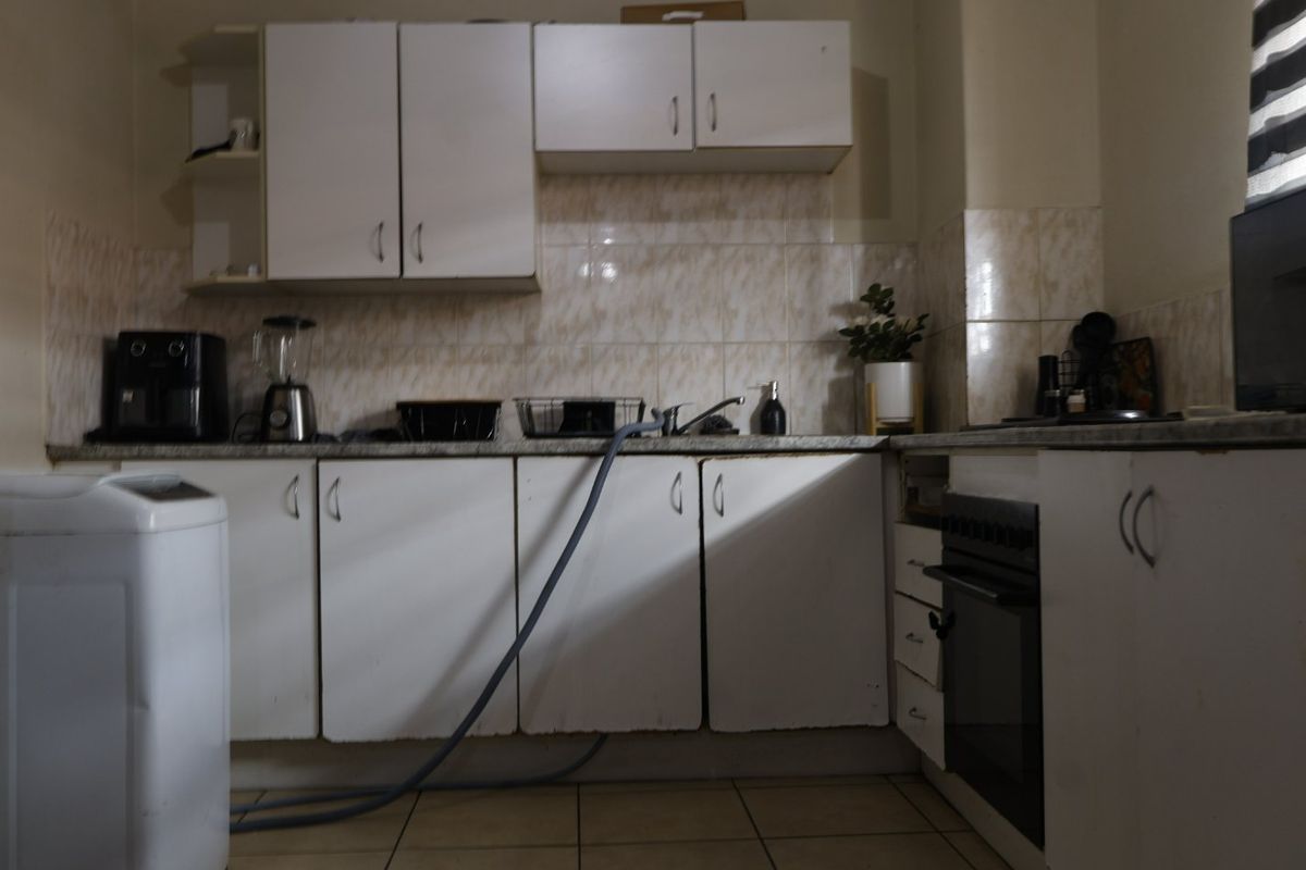 A functional kitchen featuring white built-in cabinetry, a tiled backsplash, and a built-in oven, offering a practical layout with potential for cosmetic updates.