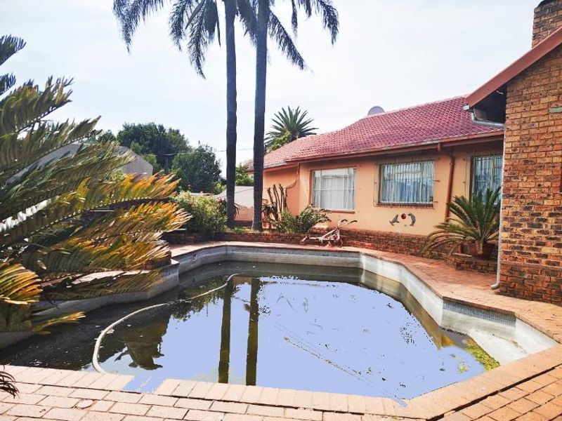 Rear exterior view featuring a swimming pool with brick paving and a brick-clad house facade with a tiled roof.