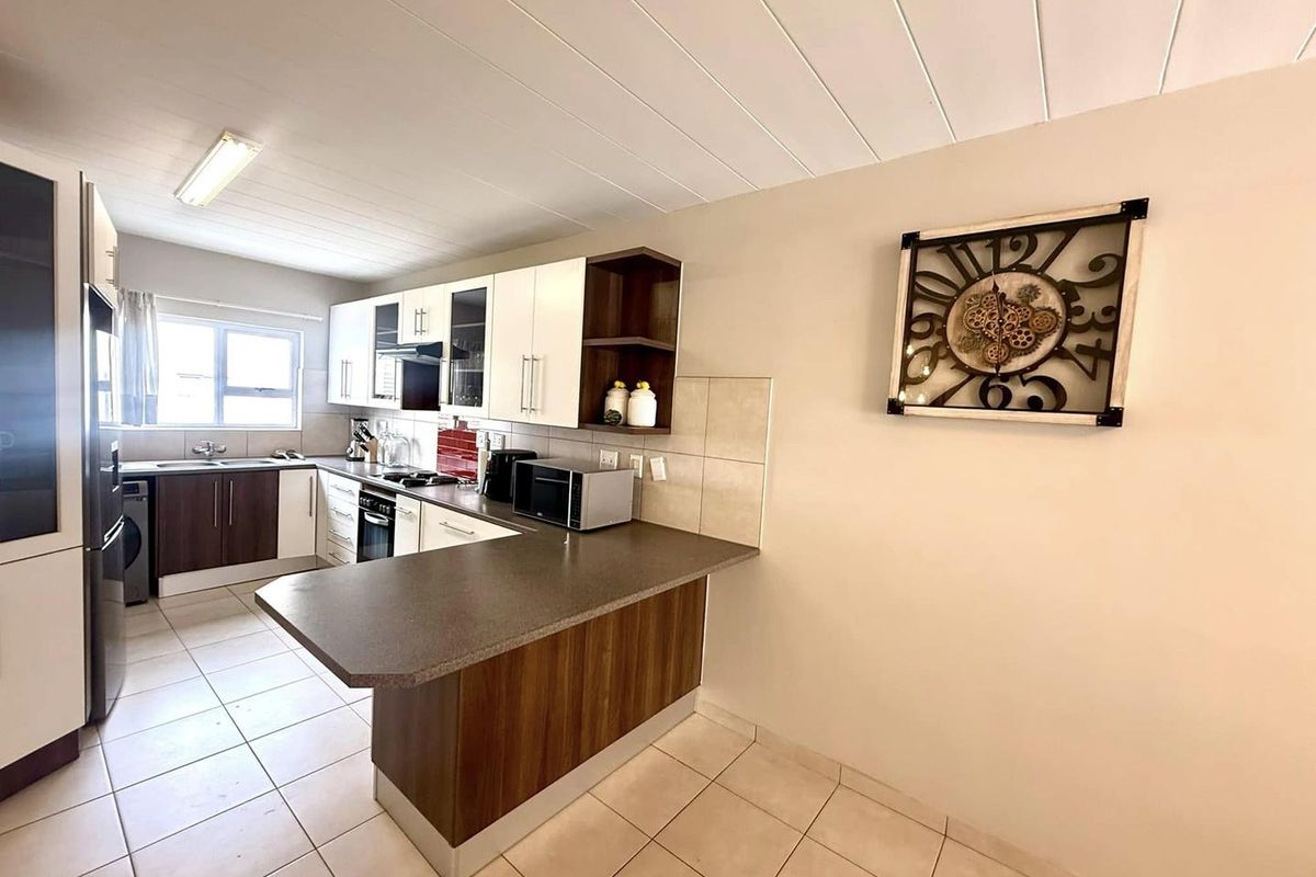 A functional kitchen featuring a breakfast bar, built-in cabinetry, tiled flooring, and a tiled backsplash, offering a practical layout for daily meal preparation.