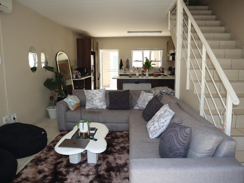 Open-plan living area featuring a kitchen with island, tiled flooring, and a staircase leading to the upper level.
