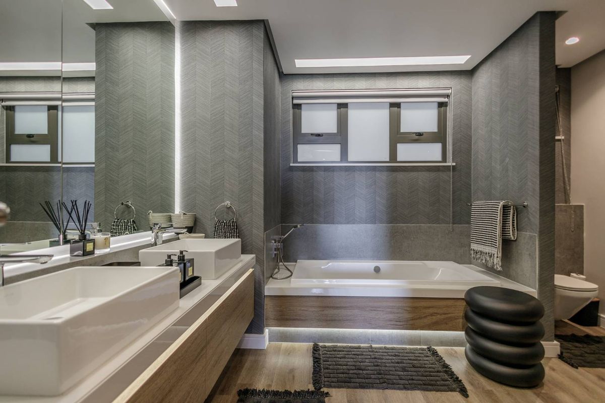 Modern bathroom featuring a double vanity with vessel sinks, a built-in bathtub with wood-look paneling, and contemporary textured wall finishes.