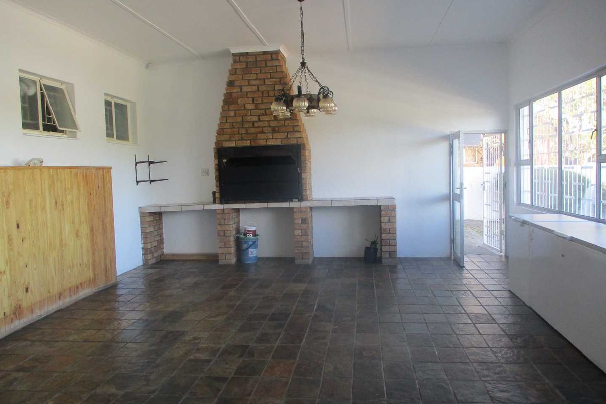 Spacious entertainment area featuring a built-in brick fireplace, tiled flooring, and direct access to the exterior.