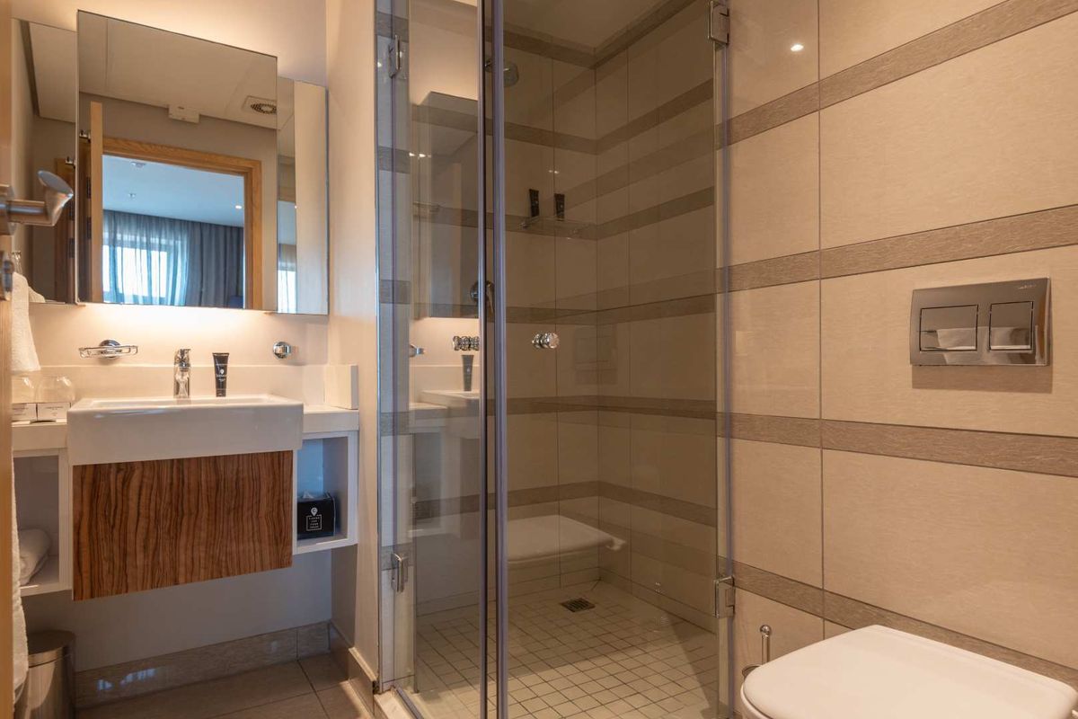 Modern bathroom featuring a glass-enclosed shower, wall-mounted vanity with integrated basin, and a concealed cistern toilet with tiled walls.