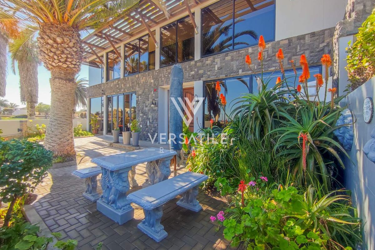 A well-maintained rear patio area featuring stone cladding, paved flooring, and a covered pergola structure, providing an inviting outdoor living space.