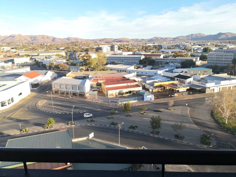 Elevated panoramic view overlooking the surrounding urban landscape, commercial buildings, and distant mountain ranges.